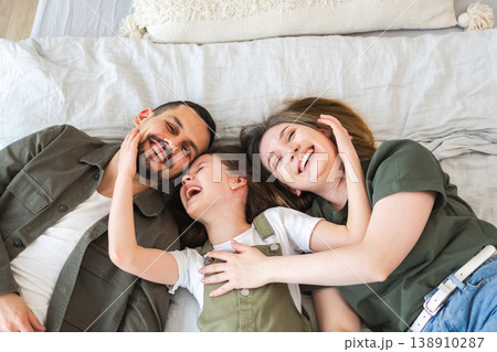 Happy family at home. Mother father children daughter relaxing in bed at home indoor. Mom dad parents kid girl relax playing hugging having fun together. Family smiling laughing enjoying tender moment Happy family at home. Mother father children daughter relaxing in bed at home indoor. Mom dad parents kid girl relax playing hugging having fun together. Family smiling laughing enjoying tender moment 138910287