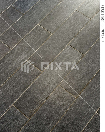 Dark wood flooring inside building, decorative texture background for design. Long planks arranged in neat pattern. Surface reflects light slightly, highlighting texture and grains of wood 138910535