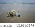 Ocean's Unwanted Guest: A weathered plastic bottle lies stranded on the sandy shore, a stark reminder of environmental pollution and the urgent need for conservation. 138910576