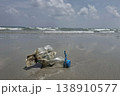 Ocean's Unwanted Guest: A weathered plastic bottle lies stranded on the sandy shore, a stark reminder of environmental pollution and the urgent need for conservation. 138910577