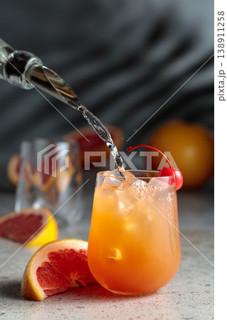 Strong alcohol is poured into a glass with ice and grapefruit juice. Strong alcohol is poured into a glass with ice and grapefruit juice. 138911258