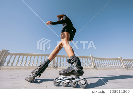 Low angle view of woman rollerblading under blue sky Low angle view of woman rollerblading under blue sky 138911869