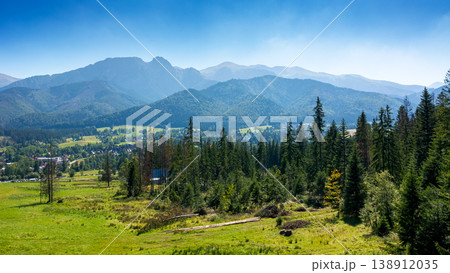 forest on the hill in mountain landscape in summer. beautiful countryside view with grassy pasture and tatra mountain ridge under blue sky on a sunny day. zakopane village in the valley. rural europe forest on the hill in mountain landscape in summer. beautiful countryside view with grassy pasture and tatra mountain ridge under blue sky on a sunny day. zakopane village in the valley. rural europe 138912035