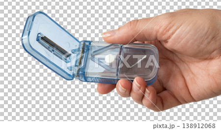 Hand holding compact plastic pill splitter and storage container with built-in blade and compartments, representing medication management and dosage accuracy Hand holding compact plastic pill splitter and storage container with built-in blade and compartments, representing medication management and dosage accuracy 138912068