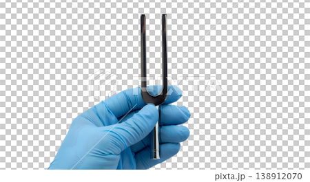 Hand holding a metal two-pronged tuning fork, isolated on transparent background, representing acoustic testing, audiology, and neurological examination 138912070