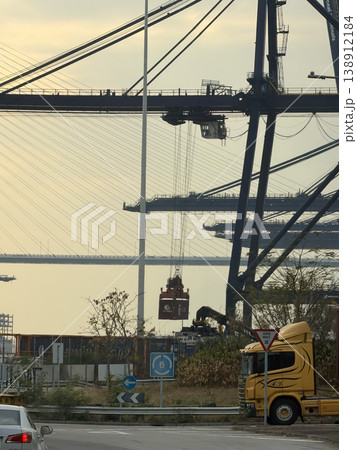 Container ship loading and unloading with cranes at a busy port terminal Container ship loading and unloading with cranes at a busy port terminal 138912184