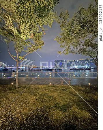 Nighttime harbor view with boats and city skyline illuminated by vibrant lights Nighttime harbor view with boats and city skyline illuminated by vibrant lights 138912188