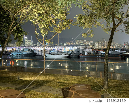 Nighttime harbor view with boats and city skyline illuminated by vibrant colorful lights Nighttime harbor view with boats and city skyline illuminated by vibrant colorful lights 138912189