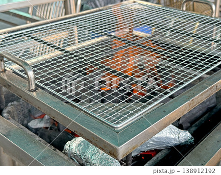 Close up of a hot grill grate over glowing embers and charcoal briquettes 138912192