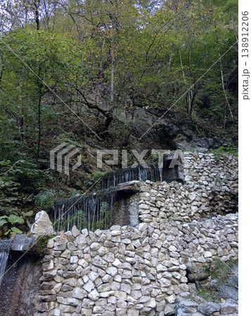 Step waterfall, North Ossetia, Russia, bright summer day. Cascading water flowing down natural stone steps in a green mountain landscape Step waterfall, North Ossetia, Russia, bright summer day. Cascading water flowing down natural stone steps in a green mountain landscape 138912206