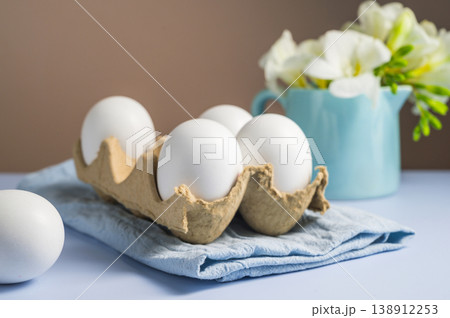 Easter eggs background. White eggs in cardboard box and freesias flowers in a vase. Spring holiday 138912253