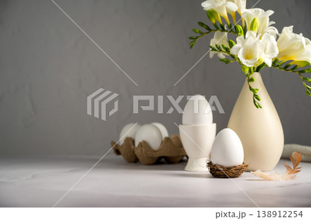 Spring, Easter background. White freesias flowers in a vase with white eggs. Spring, Easter background. White freesias flowers in a vase with white eggs. 138912254