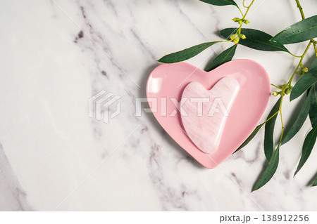 Rose quartz gua sha and eucalyptus leaves, abstract beauty photo. Copy space 138912256