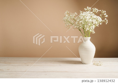 White floral background. Soft home decor, vase with white small flowers on white background, copy space 138912432