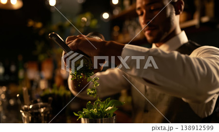Bartender expertly muddling fresh herbs in a dimly lit cocktail bar 138912599