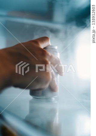 Hand reaching for a cold can inside a frosty refrigerator 138912603
