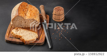 Artisan bread loaf with slices and bread knife on wooden board, rustic bakery composition Artisan bread loaf with slices and bread knife on wooden board, rustic bakery composition 138912922