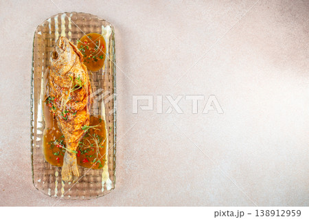 Top view of whole fried dorado fish with spicy sauce on glass plate and copy space for seafood restaurant advertising Top view of whole fried dorado fish with spicy sauce on glass plate and copy space for seafood restaurant advertising 138912959