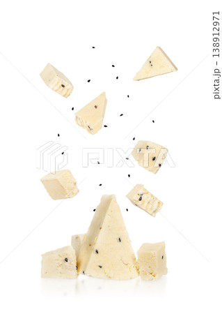 Cheese pieces falling isolated on white background, soft dairy cubes with black cumin seeds Cheese pieces falling isolated on white background, soft dairy cubes with black cumin seeds 138912971