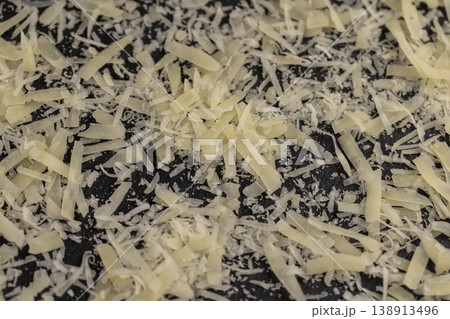 ripe cheese grated into small pieces for cooking pasta or pizza, grated piece of yellow quality cheese as an ingredient for a large dish ripe cheese grated into small pieces for cooking pasta or pizza, grated piece of yellow quality cheese as an ingredient for a large dish 138913496