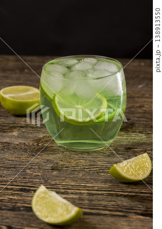 one cold lime-flavored carbonated drink with lots of gas bubbles and whole pieces of fresh sour lime, sweet green-colored carbonated drink poured into a glass with ice one cold lime-flavored carbonated drink with lots of gas bubbles and whole pieces of fresh sour lime, sweet green-colored carbonated drink poured into a glass with ice 138913550