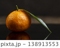 one fresh orange small tangerine with green leaves are reflected on a black mirror , a group of ripe sweet tangerines with green leaves with reflection on a black glass 138913553