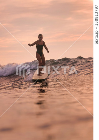 Calm Woman Balances On Surfboard As Bright Sunset Illuminates Ocean Calm Woman Balances On Surfboard As Bright Sunset Illuminates Ocean 138913797