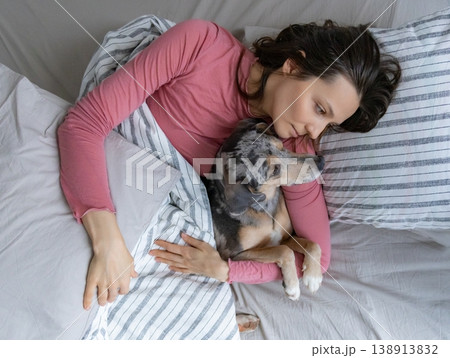 young woman sleeps with spotted dog on bed, girl and dog sleep comfortably together. 138913832