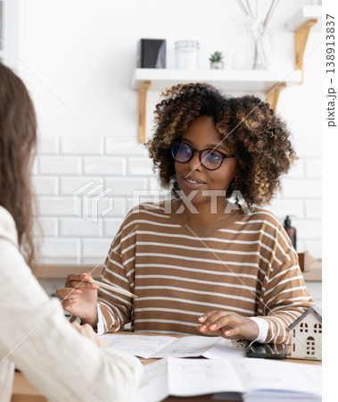 confident curly haired woman with curly dark hair, designer or realtor, shows mock up house. confident curly haired woman with curly dark hair, designer or realtor, shows mock up house. 138913837