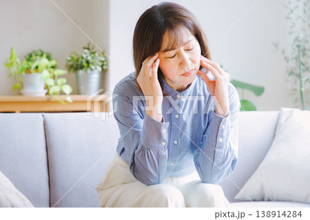 頭痛でこめかみを押さえるミドル女性 138914284