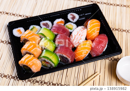 On table there is black rectangular plate with set with maki - uramaki and nigari On table there is black rectangular plate with set with maki - uramaki and nigari 138915982