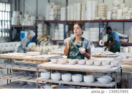 Girl ceramist arranging new bowls in workshop Girl ceramist arranging new bowls in workshop 138915991