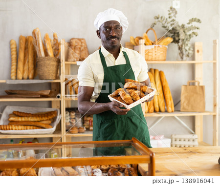 Male baker holding a tray of freshly baked croissants 138916041