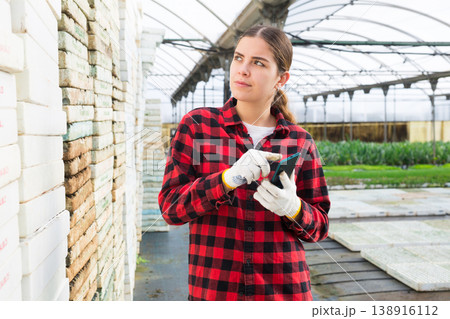 Young woman farmer is typing an important message on her mobile phone Young woman farmer is typing an important message on her mobile phone 138916112