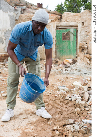 Upset afro american man observing the destruction of his home Upset afro american man observing the destruction of his home 138916114