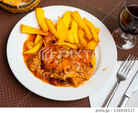 Stewed rabbit pieces served with side dish of fries 138916115