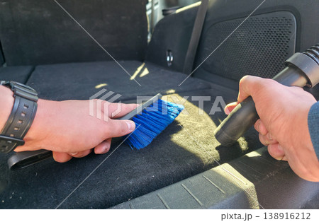 A young man vacuums and cleans the interior of a car. Car cleaning and detailing. High quality photo A young man vacuums and cleans the interior of a car. Car cleaning and detailing. High quality photo 138916212