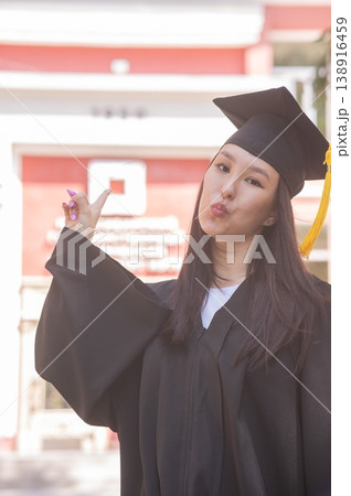 Happy young asian woman in graduation gown. Happy young asian woman in graduation gown. 138916459