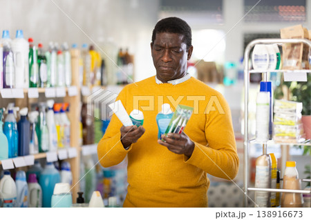African man decided to buy dental care kit, looking for something in window African man decided to buy dental care kit, looking for something in window 138916673