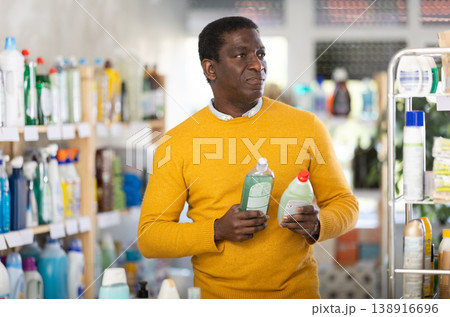 Male shopper selects dishwashing sponges in the household goods section of supermarket Male shopper selects dishwashing sponges in the household goods section of supermarket 138916696