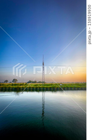 A Tranquil Reflection of a Communication Tower at Sunset, Bathing the Scene in Orange and Blue 138919930
