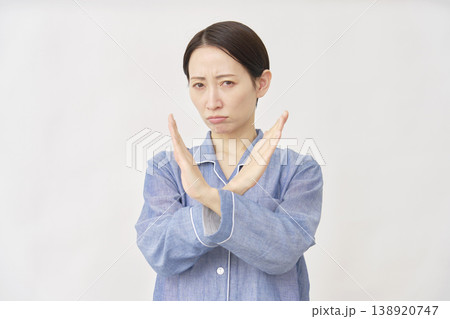 腕でばつ印のジェスチャーをするパジャマを着た女性　白バック 138920747