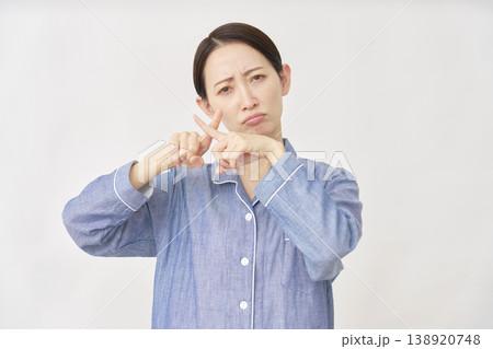 指でばつ印のジェスチャーをするパジャマを着た女性　白バック 138920748