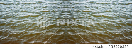 Water abstract banner background. Panoramic view of rippled water surface with symmetrical reflection. Dark murky river or lake water texture. aquatic background with small waves and copy space Water abstract banner background. Panoramic view of rippled water surface with symmetrical reflection. Dark murky river or lake water texture. aquatic background with small waves and copy space 138920839
