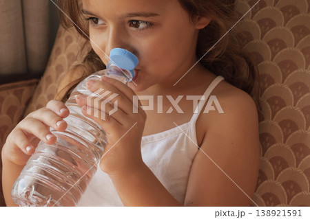Product innovation: close-up of a girl drinking from a bottle with a modern attached closure 138921591