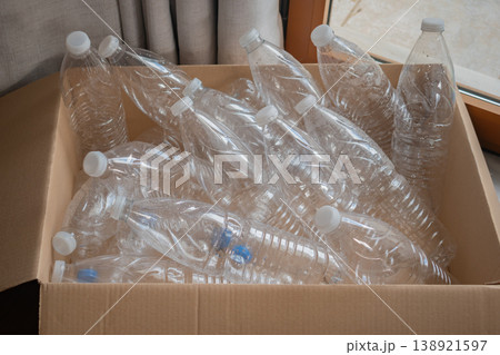 Clear plastic water bottles are packed in a cardboard box ready for recycling at a local facility Clear plastic water bottles are packed in a cardboard box ready for recycling at a local facility 138921597