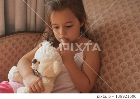 Pensive portrait: a young girl with a teddy bear, lost in quiet thought and contemplation 138921600