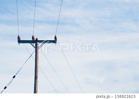 Single timber electric pylon with wires under a cloudy sky. Minimalist industrial silhouette with vast copy space for energy crisis, utility tariffs or blackout news 138921623