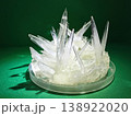 Sharp, translucent crystals grow in a cluster on a petri dish, showcasing intricate geometric patterns and sharp edges against a dark green background 138922020