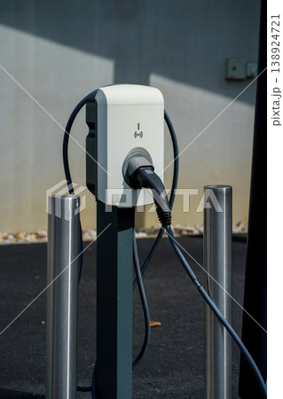 Electric car charging station with plugged cable in parking area, EV infrastructure, clean energy transport, sustainable mobility technology outdoors 138924721